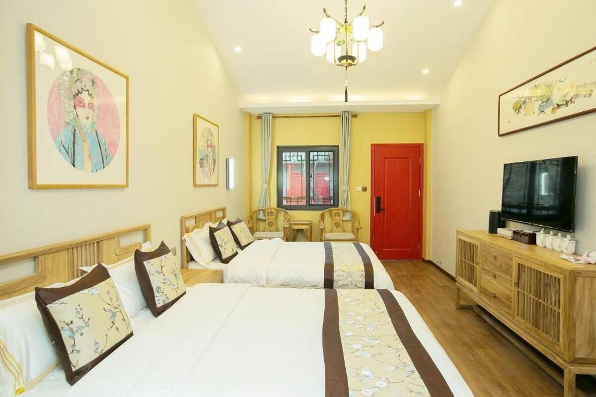 Una habitación de hotel con dos camas, un televisor, un armario de madera y obras de arte en las paredes.