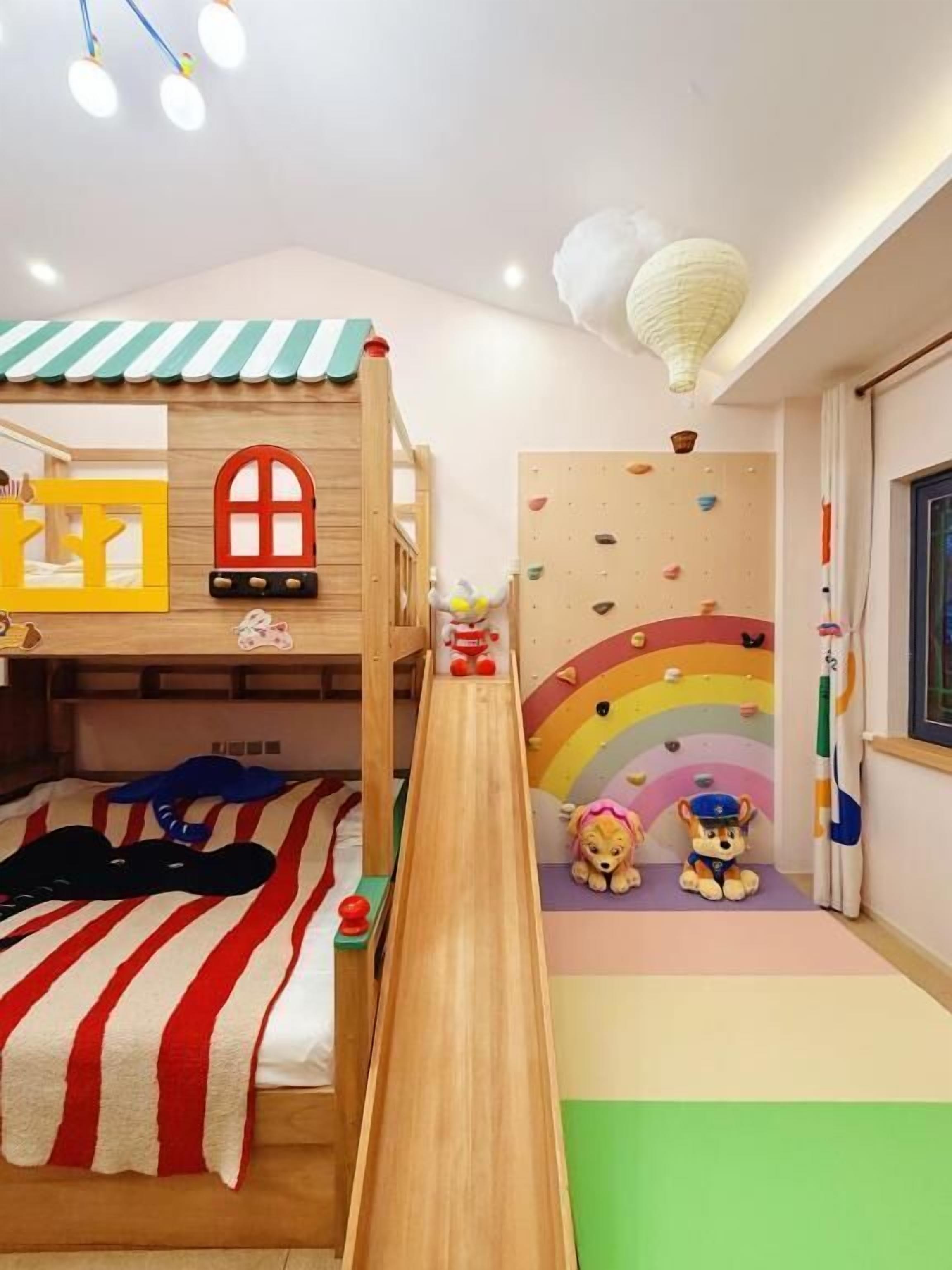 A children's playroom with bunk beds, a slide, and a climbing wall.