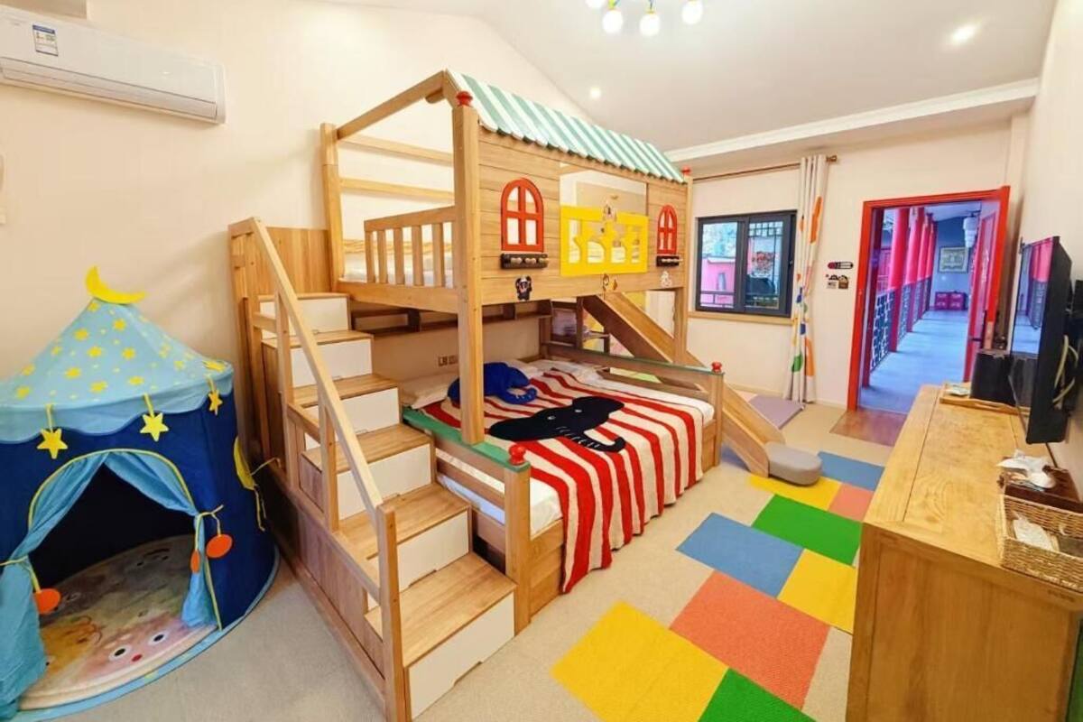 Habitación infantil con literas, una casita de juegos y una carpa con forma de estrella.