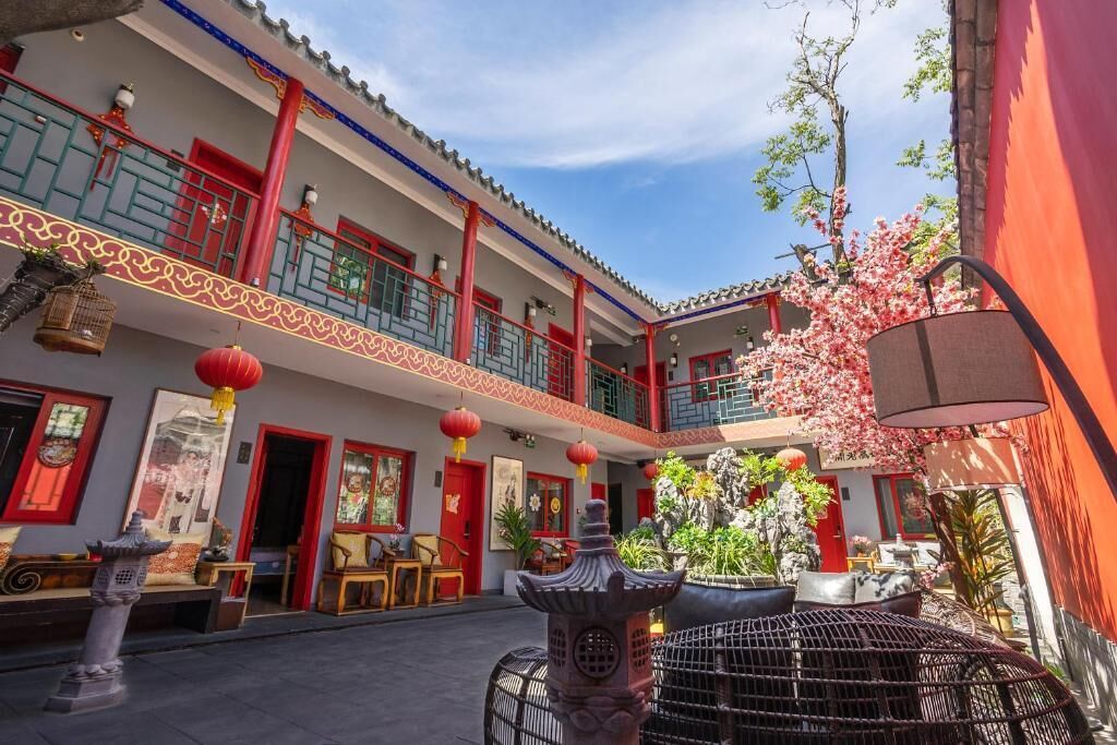 A courtyard with traditional architecture, including red doors, lanterns, and a stone lantern.