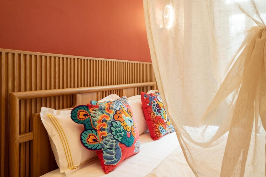 A bed with a wooden headboard, a mosquito net, and colorful pillows.