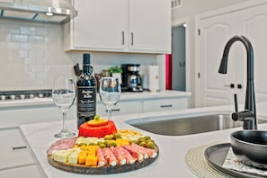 A kitchen counter with a charcuterie board, wine glasses, and a bottle of wine.
