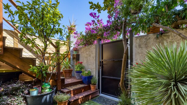 A patio with potted plants, a wooden staircase, and a sliding glass door.
