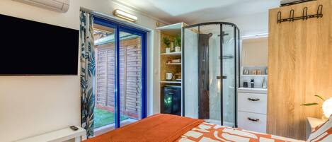 A bedroom with a bed, a wardrobe, a bathroom, and a small kitchenette.