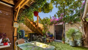 A patio with a table, chairs, potted plants, and a staircase.