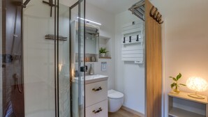 A modern bathroom with a glass shower enclosure, a white sink, and a toilet.