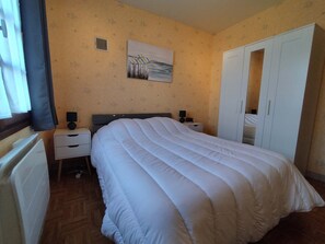 A bedroom with a bed, a nightstand, a bedside table, a wardrobe, and a wall-mounted artwork. - Maison de la Boirie (Saint-Denis-d'Oléron)