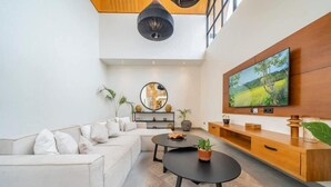 Een moderne woonkamer met een bank, salontafel, televisie en een houten dressoir.