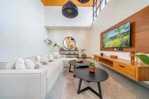 Ein modernes Wohnzimmer mit Sofa, Couchtisch, Fernseher und einer Holzkonsole.