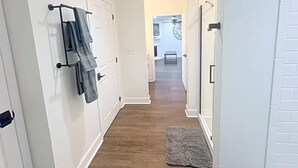 Un corridoio con pareti bianche, pavimento in legno e tappeto grigio.