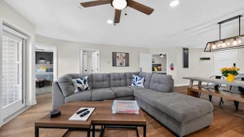 A modern living room with a sectional sofa, a wooden coffee table, and a ceiling fan.