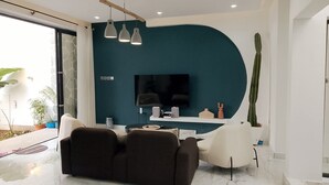 Ein modernes Wohnzimmer mit Fernseher, Sitzgelegenheiten und einem außergewöhnlichen Wanddesign.