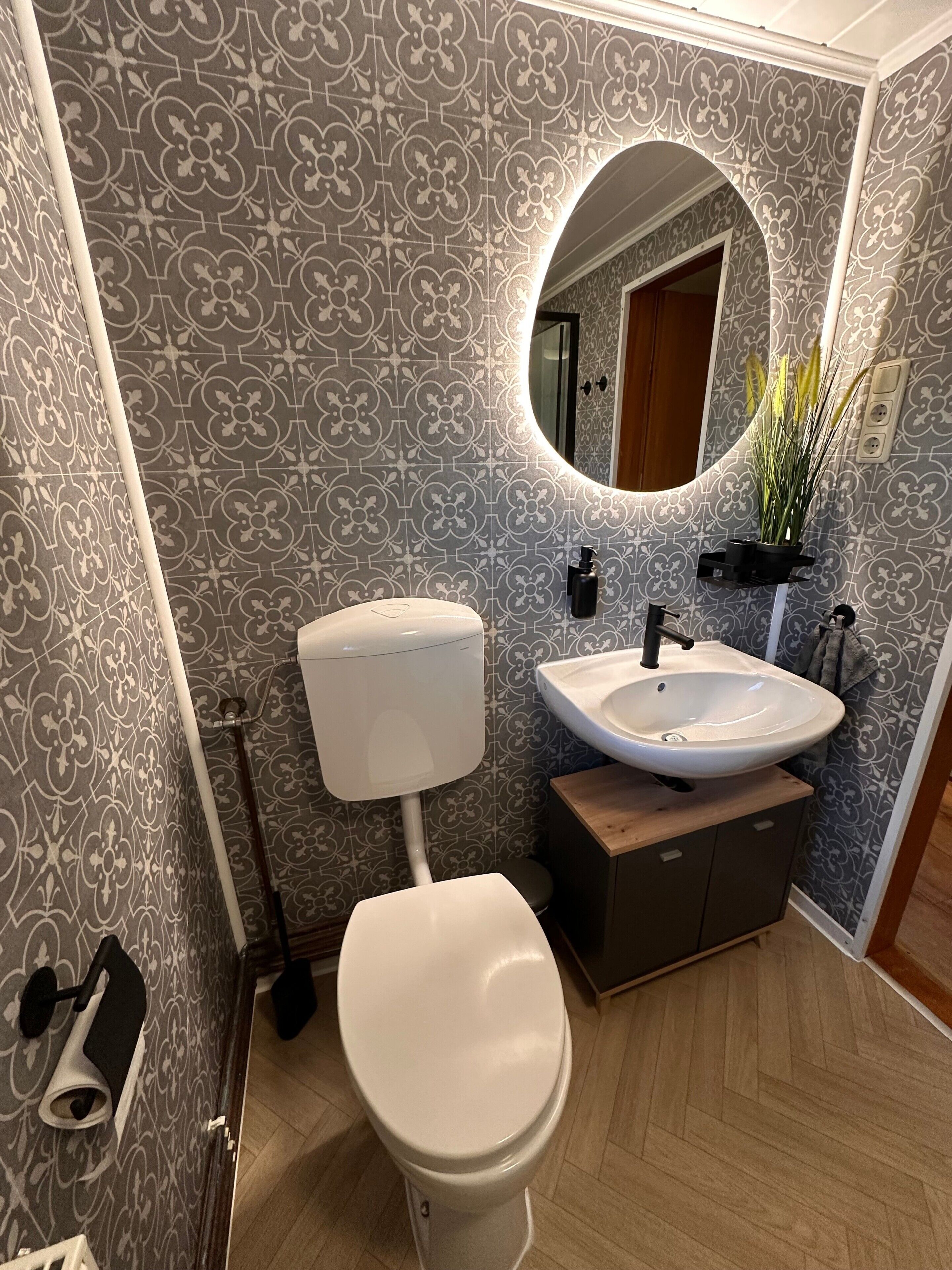 A bathroom with a toilet, sink, and mirror.
