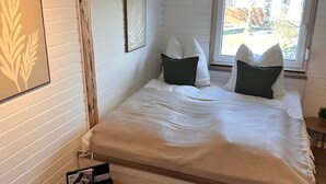 A bedroom with a bed, pillows, a bedside table, and a window. - Coastal Bliss Holiday Home on the Großer Meer in East Frisia (Südbrookmerland)