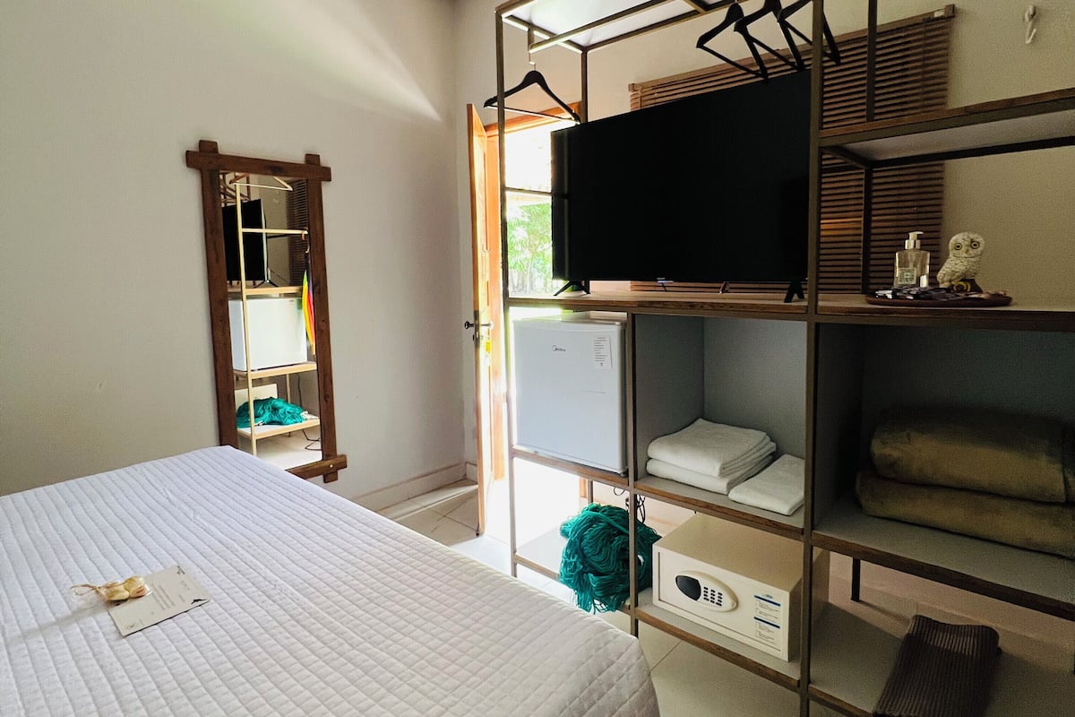 A bedroom with a bed, a TV on a shelf, a mirror, and a wardrobe.