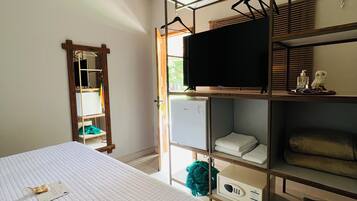A bedroom with a bed, a TV on a shelf, a mirror, and a wardrobe.