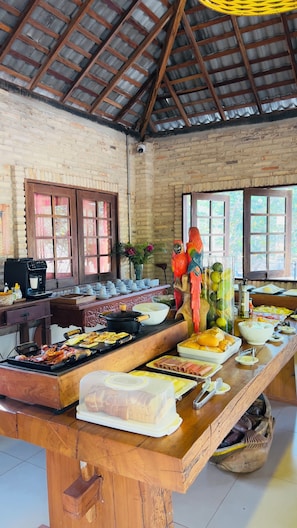 A buffet setup with various food items, a coffee machine, and decorative elements like a parrot sculpture.