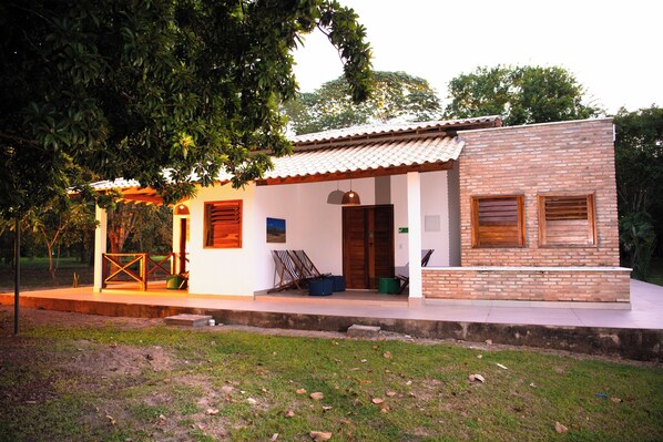 A two-story building with a brick facade, a wooden door, and a small porch area. - Nazareth Eco Hotel (José de Freitas)