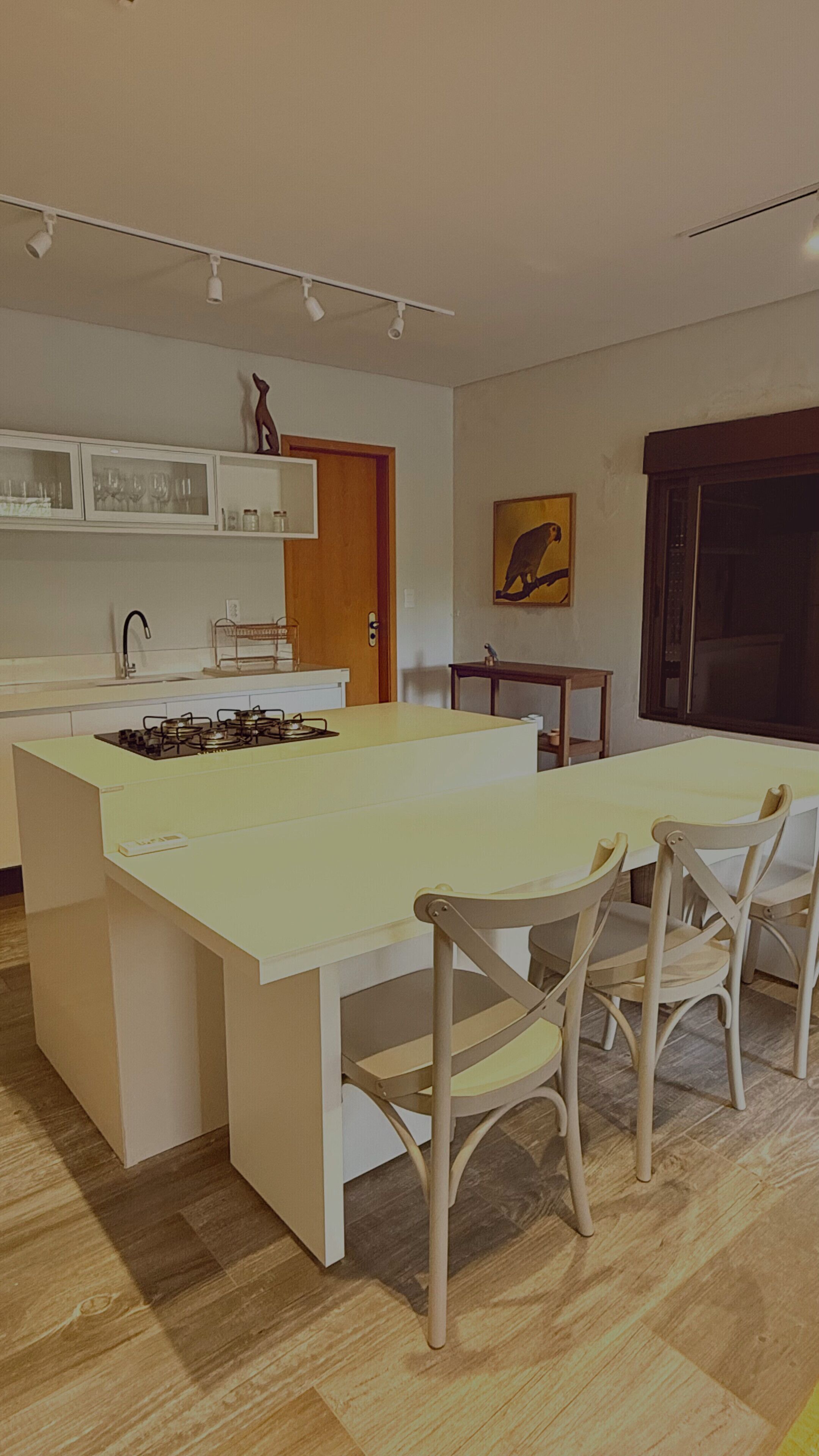 A modern kitchen with a central island, a dining table with chairs, and a small side table.
