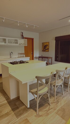 A modern kitchen with a central island, a dining table with chairs, and a small side table.