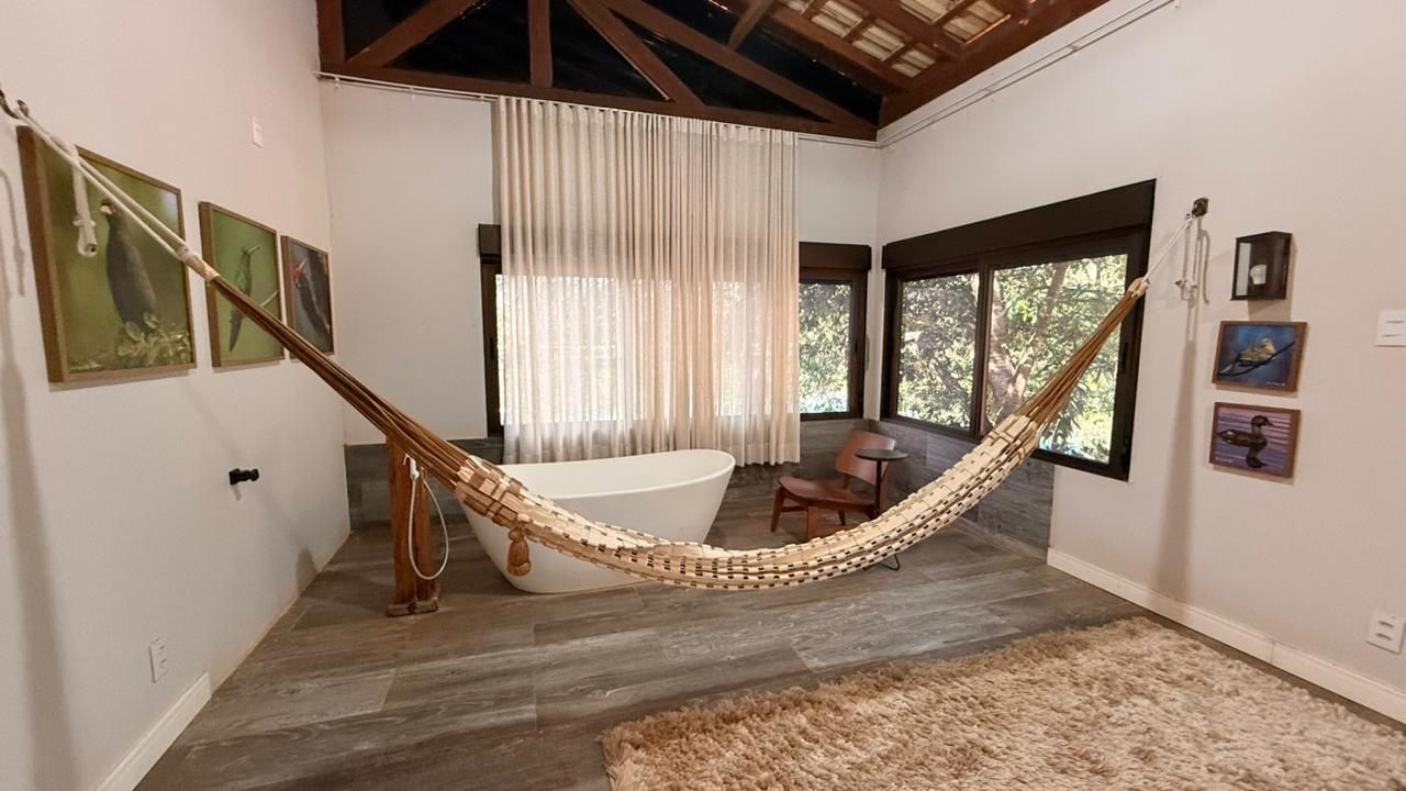 A room with a hammock, a bathtub, and artwork on the walls.