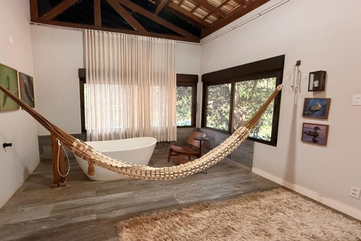 A room with a hammock, a bathtub, and artwork on the walls.
