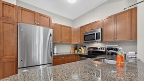A kitchen with wooden cabinets, stainless steel appliances, granite countertops, and a built-in microwave. - Mountain View w Pool and Hot Tub 2213 (Kelowna)