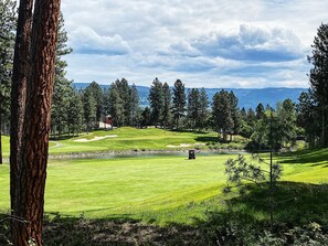 A golf course with a pond, trees, and a distant mountain view. - Mountain View w Pool and Hot Tub 2213 (Kelowna)