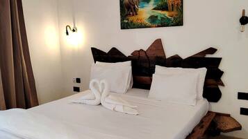 Uma cama com estrutura de madeira, roupa de cama branca e um quadro com uma paisagem tropical acima.