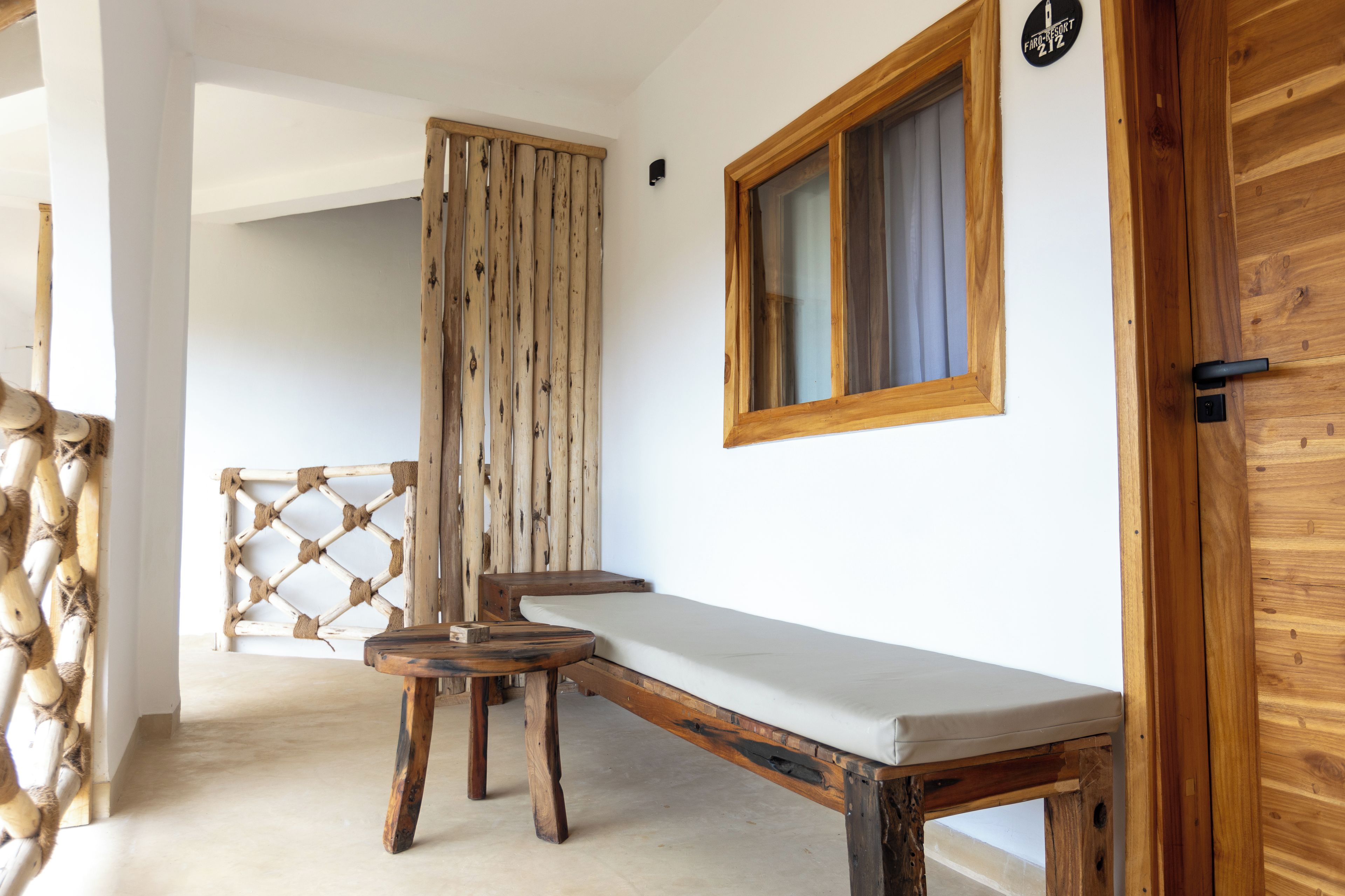 Un banco de madera con asiento acolchado, una puerta de madera con un ventanal y una pared de madera con un letrero.