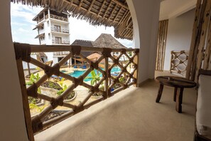 A room with a view of a pool and a thatched-roof building. - Faro Resort (Nungwi)