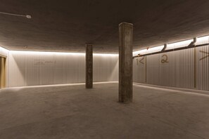 Een ruime, lege parkeergarage met betonnen pilaren en golfplaten muren.