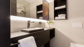 Un baño moderno con un espejo grande, un lavabo, un perchero para toallas y un estante con toallas.