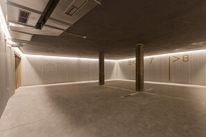 Een parkeergarage met betonnen vloeren, metalen pilaren en verlichte cijfers op de muur.
