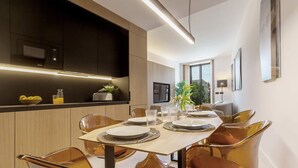 Un comedor moderno con una mesa de madera para cuatro, rodeada de sillas brillantes, una cocina con armarios oscuros y un ventanal grande.