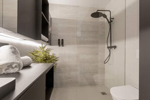Een moderne badkamer met een douche, toilet en een handdoek op het aanrecht.