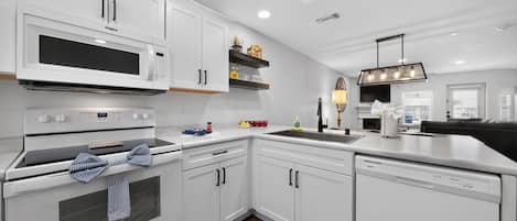 A modern kitchen with white cabinetry, a built-in microwave, and a dishwasher.