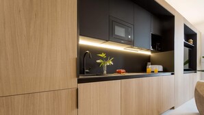 A modern kitchen with wooden cabinets, a black countertop, a microwave, and a vase with flowers.