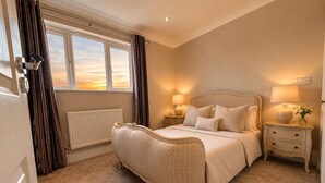 Ein Schlafzimmer mit einem großen Bett, Nachttischen, einem Heizkörper und einem Fenster mit Vorhängen.