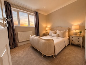 A bedroom with a large bed, bedside tables, a radiator, and a window with curtains. - Oyster Retreat | Whitstable | 200m to Beach (Whitstable)