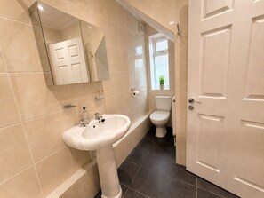 A bathroom with a pedestal sink, toilet, and a mirror above the sink. - Oyster Retreat | Whitstable | 200m to Beach (Whitstable)