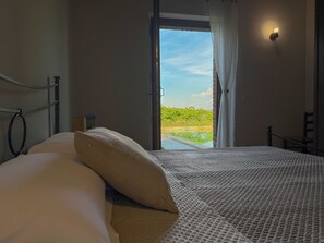 A bedroom with a bed, a view of a pool, and a window with curtains.