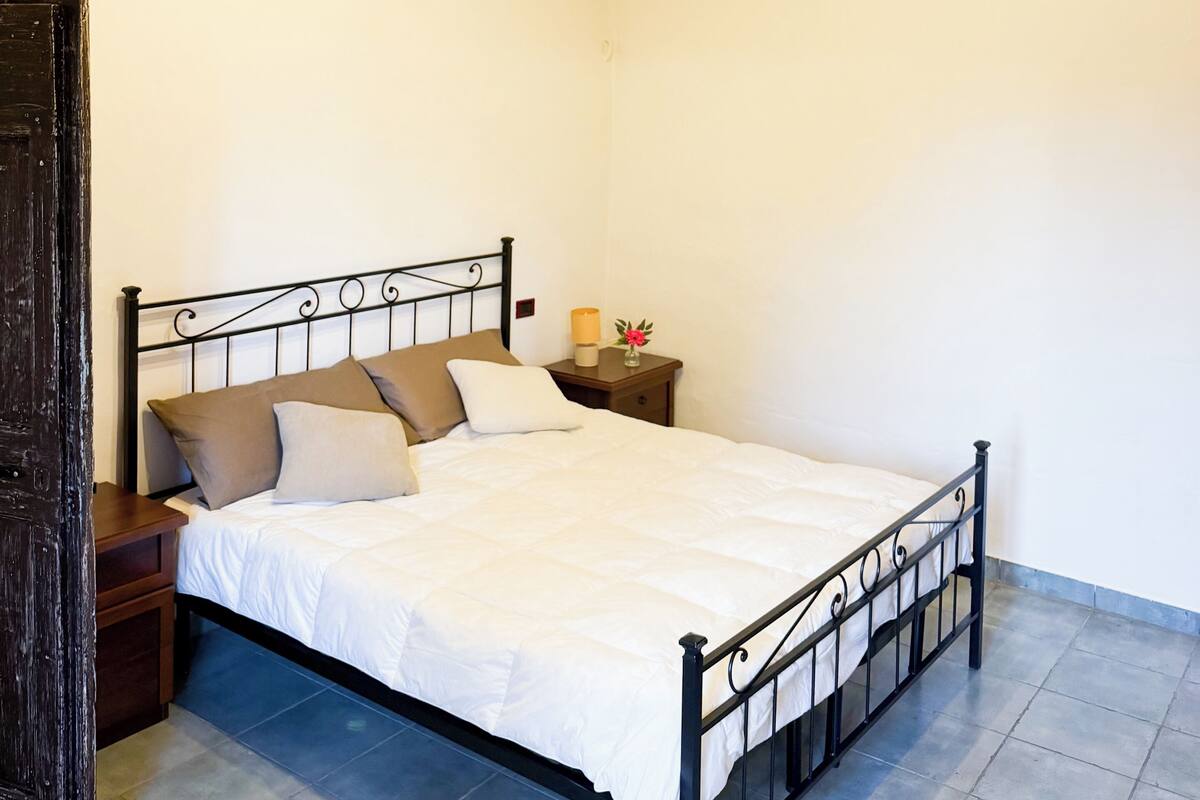 A bed with a metal frame, a nightstand with a lamp, and a wall-mounted decoration.