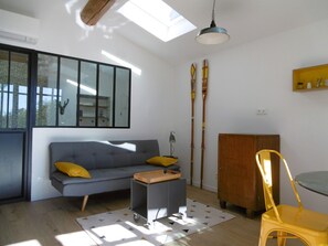 Ein modernes Wohnzimmer mit grauem Sofa, gelben Kissen, einem kleinen Tisch, einem gelben Sessel, einem Holzschrank und einem Oberlicht.
