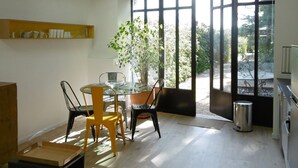 A dining area with a table, chairs, and a potted plant. - Charming holiday cottage with pool-pétanque-table tennis-foosball-BBQ-parking (Roujan)