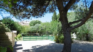 A fenced outdoor area with trees and a gravel path. - Charming holiday cottage with pool-pétanque-table tennis-foosball-BBQ-parking (Roujan)