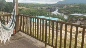 Ein Balkon mit einer Hängematte, Blick auf einen Fluss und ein entfernter Bergkamm.