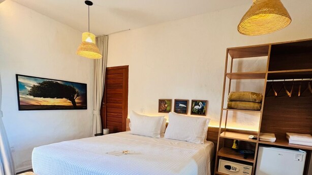 Ein Schlafzimmer mit Bett, Nachttischen, Schreibtisch, Stuhl, Lampe, einem Regal mit Gegenständen und einem Bild an der Wand.