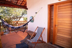 A hammock, a striped beach chair, and a wooden door on a porch.