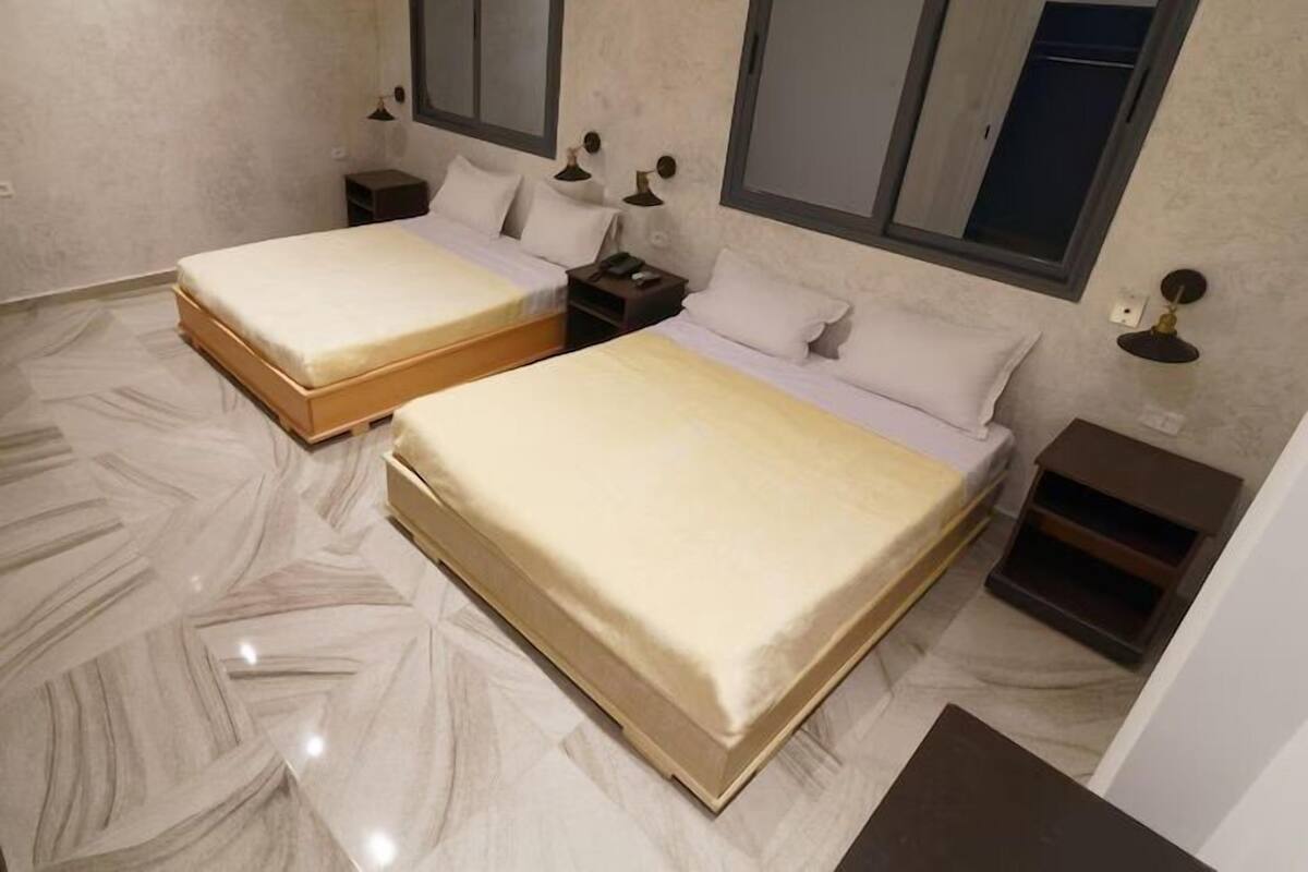 Une chambre avec deux lits, deux tables de chevet et un miroir.